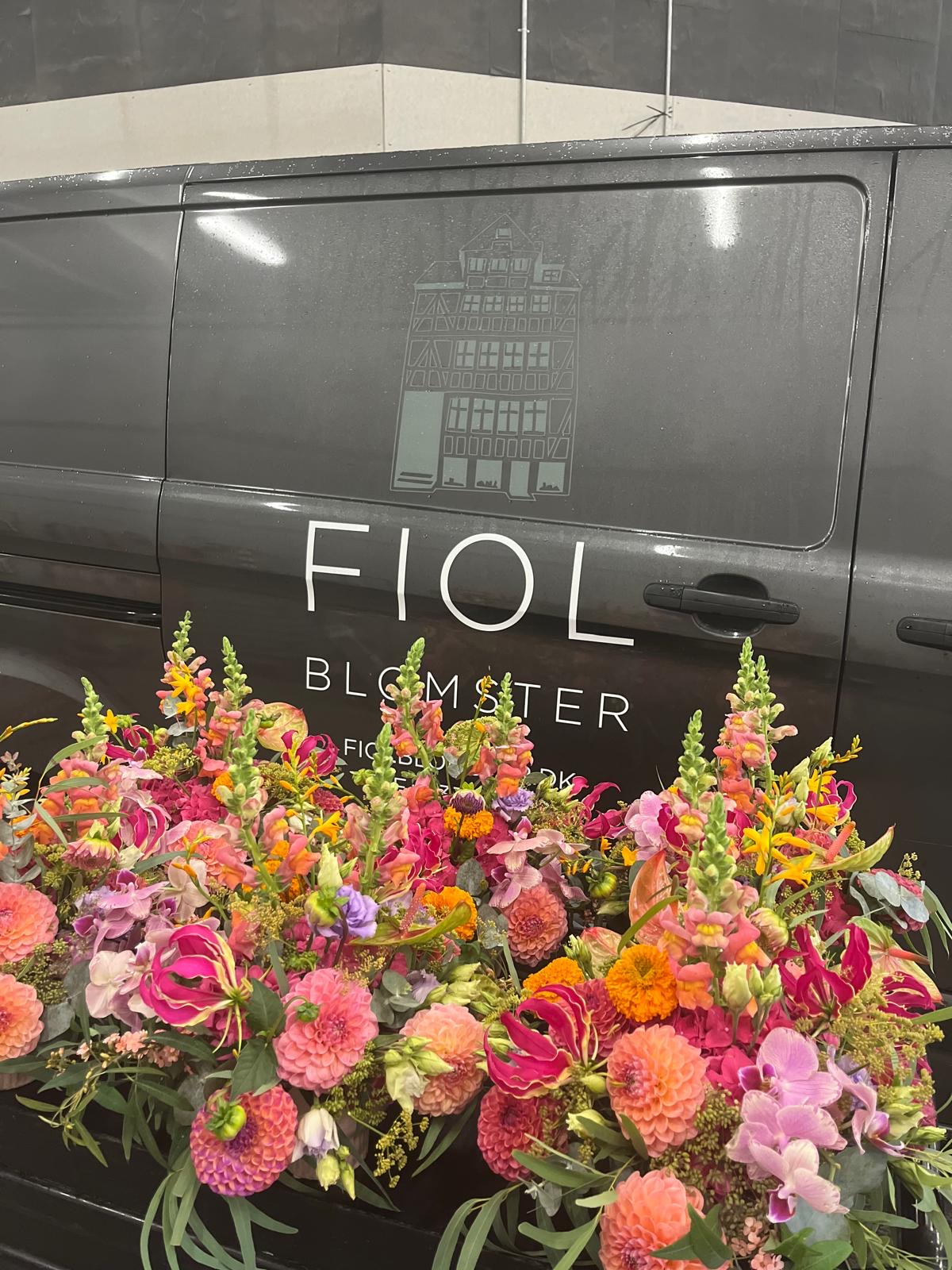 Fiol Blomsters varevogn med Fiol Blomster-written tydeligt på siden og en stor buket blomster foran